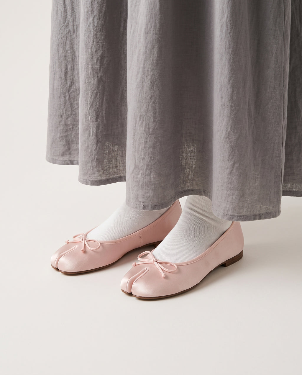 Ballerines Yubi roses portées avec une jupe grise